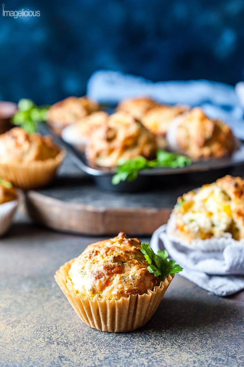 A few herbs and Cheese Muffins on a table with some napkins and herbs around them