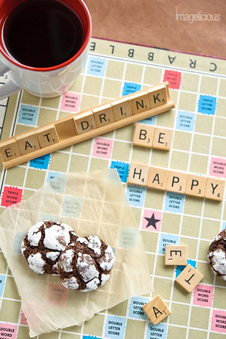 Scrabble board with a mug of coffee, words "eat drink and be happy" and two Chocolate-Mint Crackle Cookies