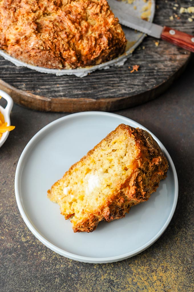 Closeup of a slice of Cheddar Soda Bread on a plate with butter melting on it.