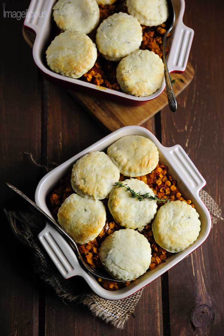 Dark/low key photography. Top down view of two dishes filled with lentil stew and topped with biscuits