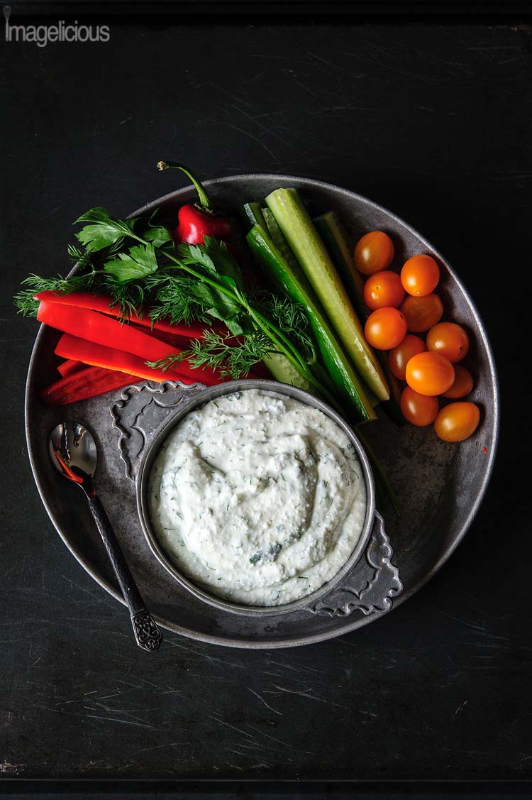 Top down photo of a plate with raw vegetables and a bowl of Cottage Cheese Dip