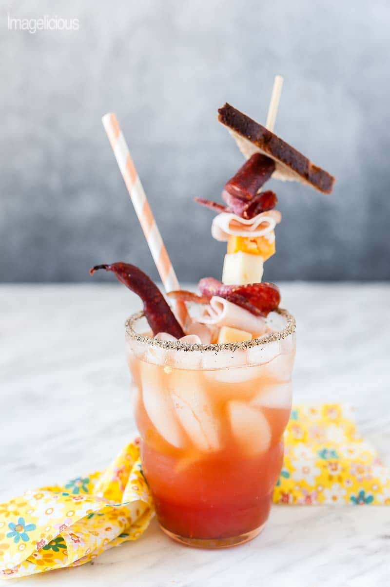Michelada with charcuterie and cheese garnish.