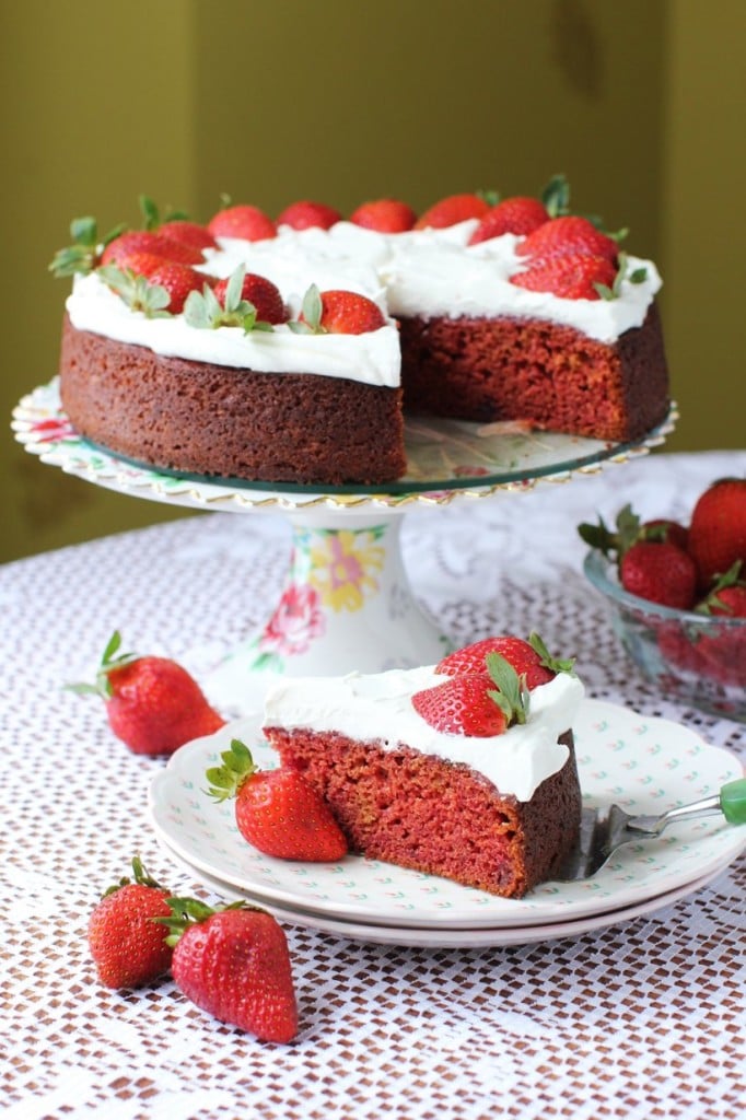 A slice of red cake with a whole cake in the background