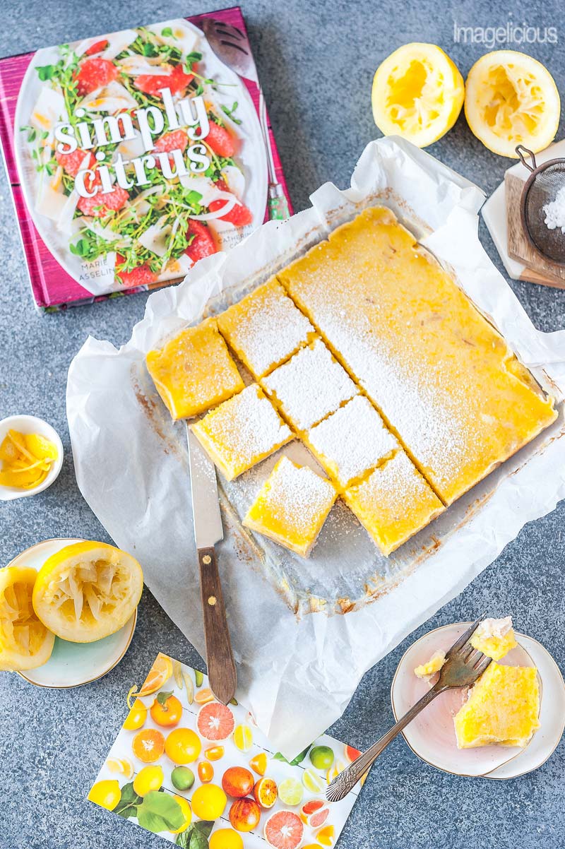 Top down view of cut up Coconut Lemon Bars with more lemons, zest around them. 