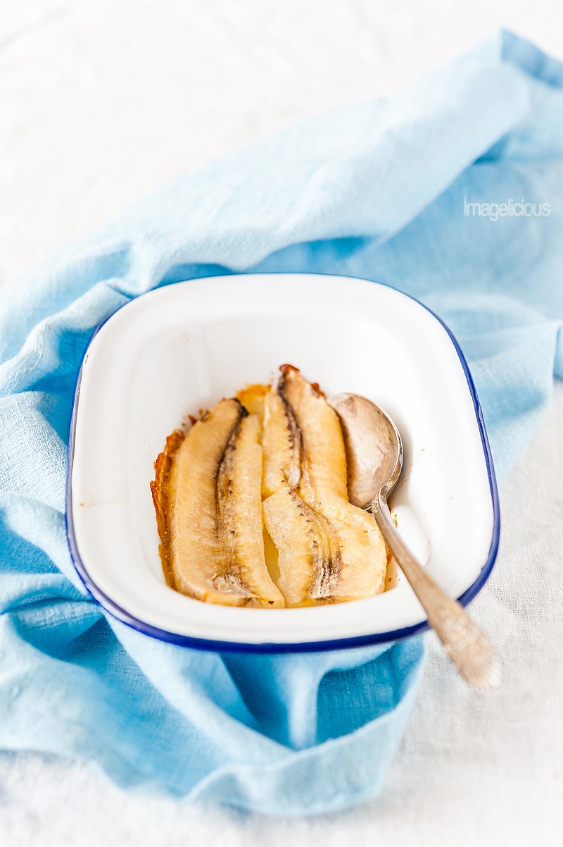 Small pan with lightly roasted bananas and a spoon on blue napkin