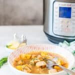 Side view photo of a bowl of beautiful Instant Pot Fish Soup with Instant Pot in the background
