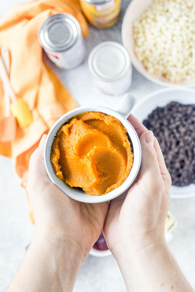 Closeup view of hands holding a bowl of canned pumpkin purée