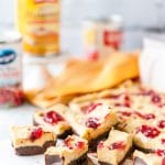 Photo of Pumpkin Cranberry Fudge cut up into serving pieces with a few cans in the background