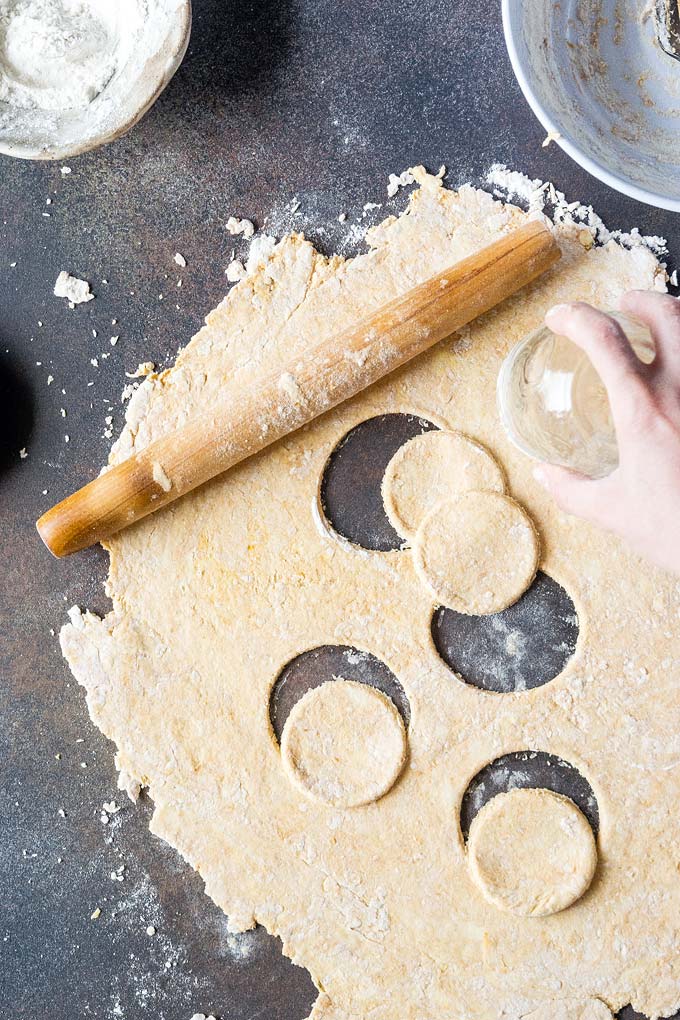 Process shot: hand is shown that is cutting out circles out of the dough with a mason jar