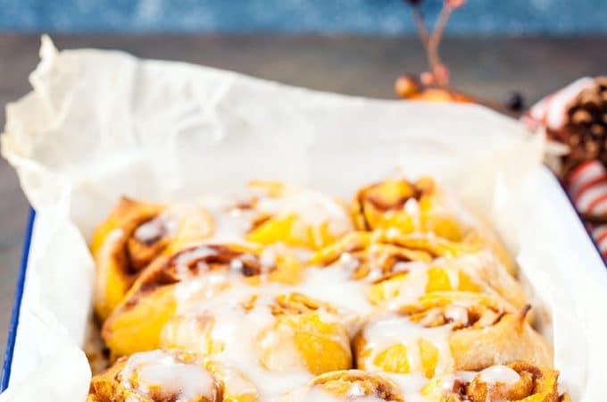 Instant Pot No Knead Pumpkin Cinnamon Rolls in a pan drizzled with glaze