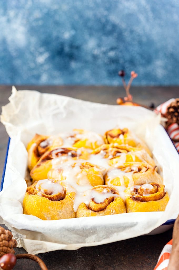 Instant Pot No Knead Pumpkin Cinnamon Rolls in a pan drizzled with glaze