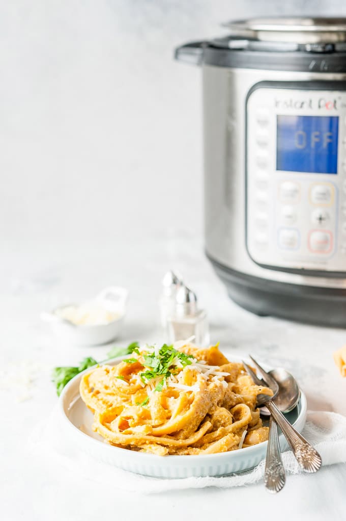 Photo of a plate of Instant Pot Pumpkin Fettuccine Alfredo with an Instant Pot in the background