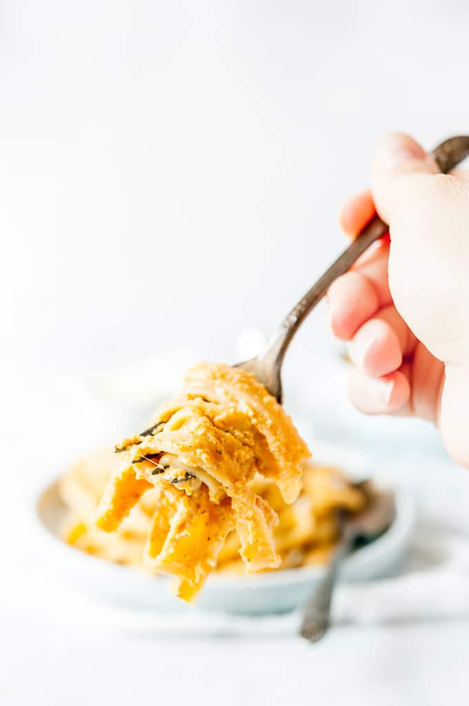 Close up of a hand holding a forkful of Instant Pot Pumpkin Fettuccine Alfredo