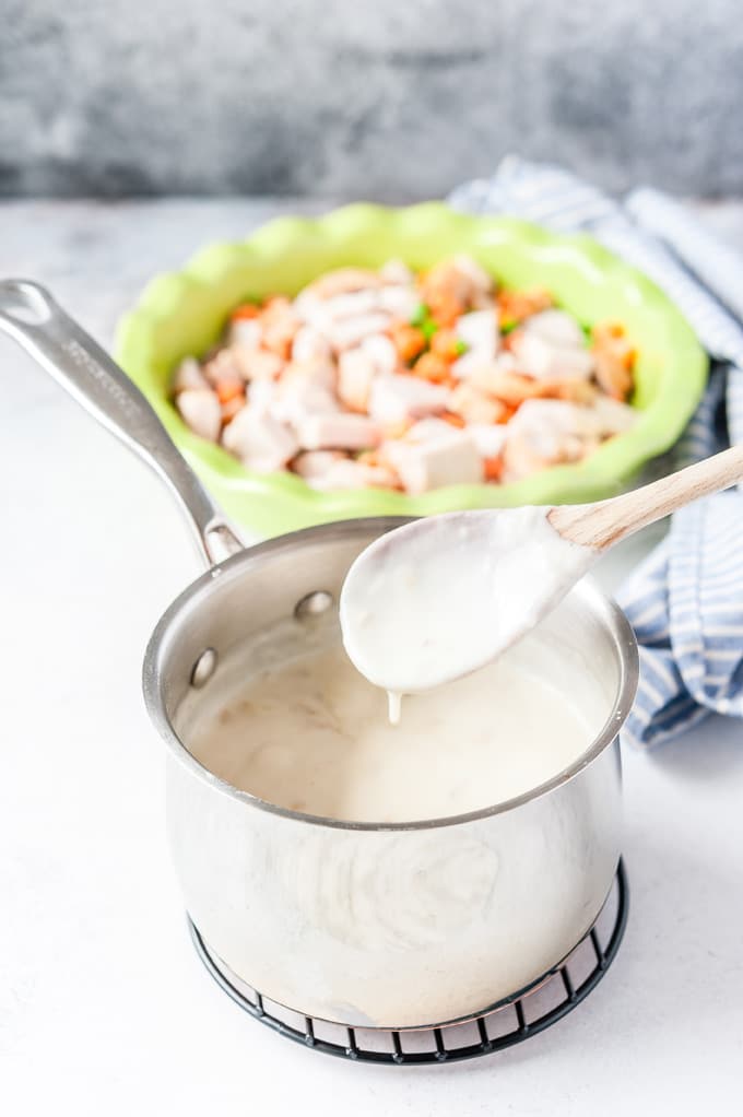 Process photo: white sauce in a pot with a spoon