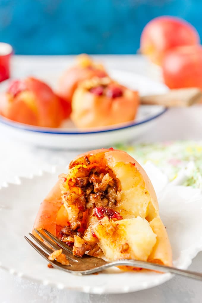 Closeup view of an Instant Pot Baked Apple cut open and the filling spilling out. More baked apples in the background
