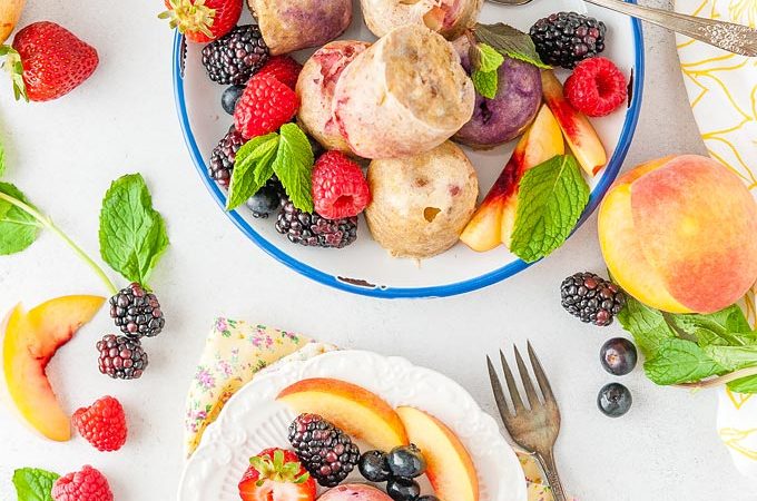Top down photo of a plate full of Instant Pot Fruity Egg Bites and a small dessert plate with just one Instant Pot Fruity Egg Bite. Lots of fruits and berries around the egg bites