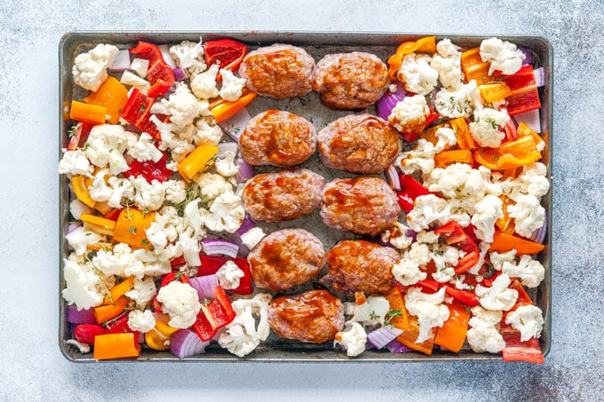 Sheet pan with mini meatloaves and vegetables ready to go into the oven