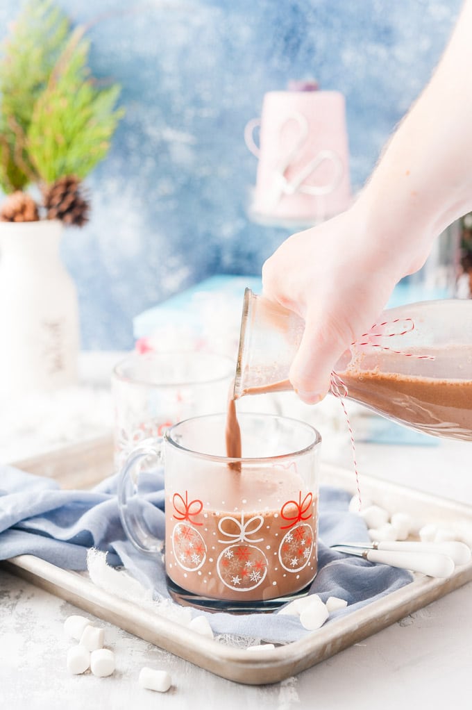 Hand pouring Instant Pot Hot Chocolate into a glass mug