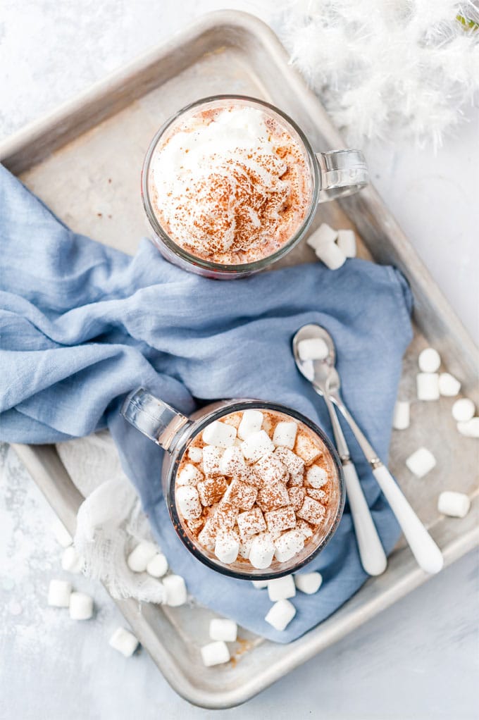 Another view of a tray with two mugs of Instant Pot Hot Chocolate and marshmallows around the mugs