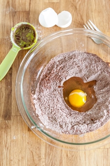 Bowl with a mixture of flour and cocoa powder and an egg cracked into it