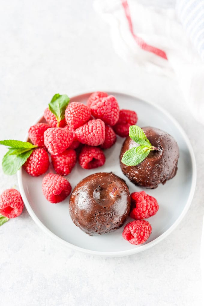 Top down view of two instant Pot Nutella Cake Bites on a plate with some raspberries on the side
