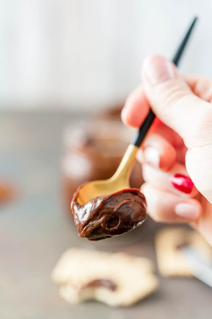 Closeup of a hand holding a spoon with some Chocolate Dulce de Leche
