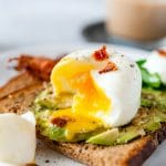 Closeup of an inside of poached egg with egg yolk dripping over avocado toast