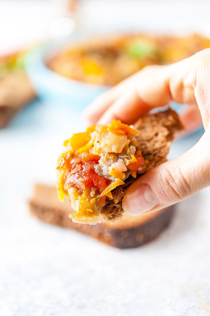 Hand holding a piece of bread with eggplant caviar