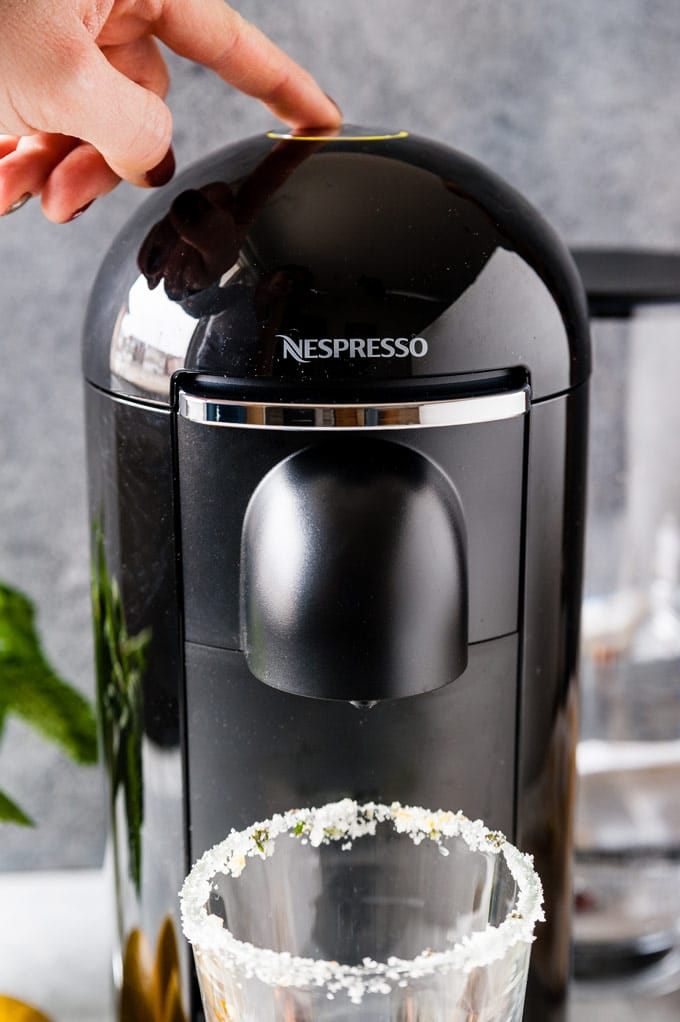 Hand pressing a button on a Nespresso machine to make coffee