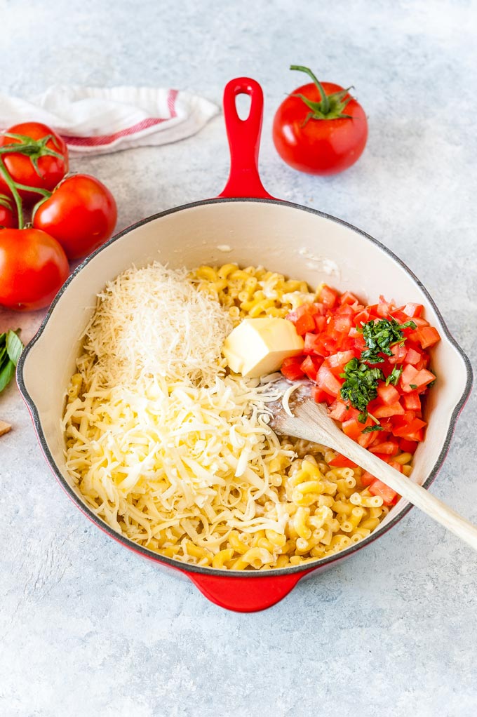 Cooked pasta in a red pan with the rest of the ingredients on top.