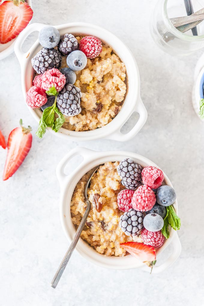 Two bowls with millet porridge with berries.
