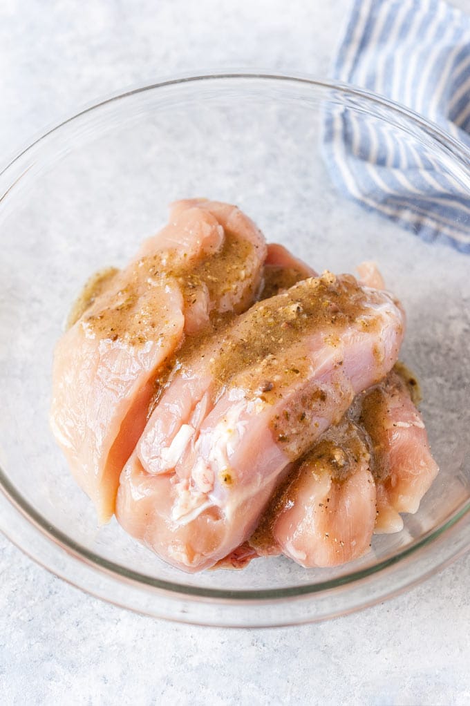 Chicken breasts marinading in a bowl.