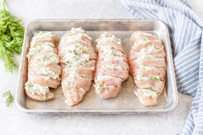Four stuffed chicken breasts on a sheet pan.
