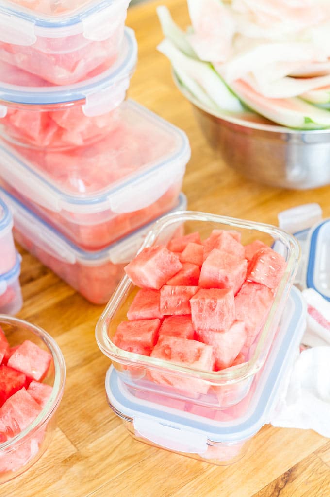 Many containers with cubed watermelon.