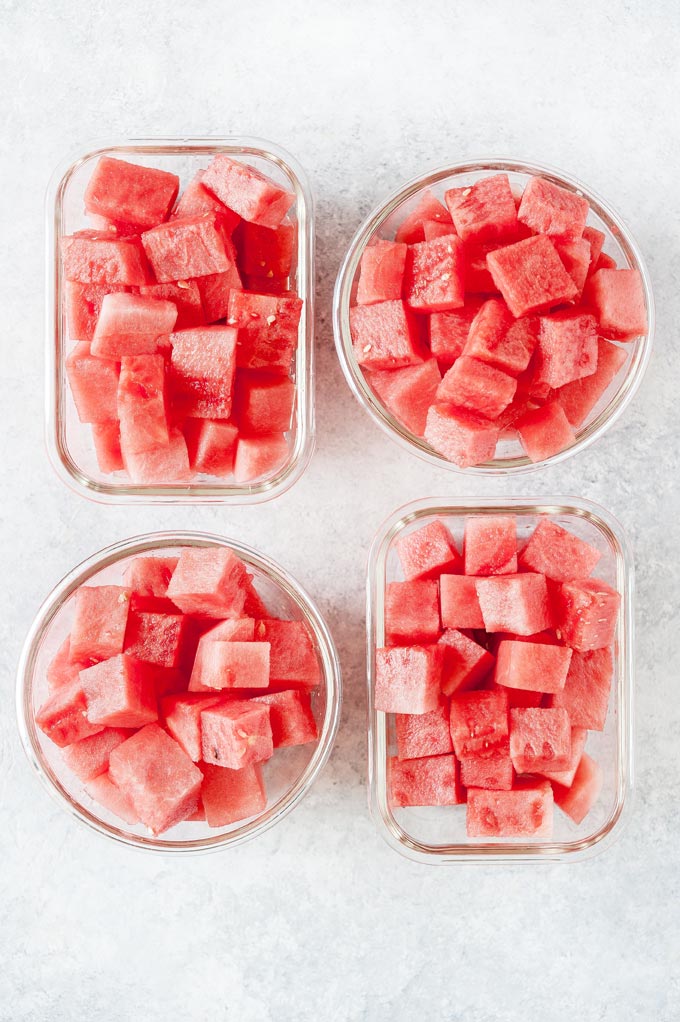 Four meal prep containers with cubed watermelon.