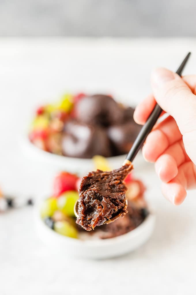 Hand holding a spoon with chocolate cake.