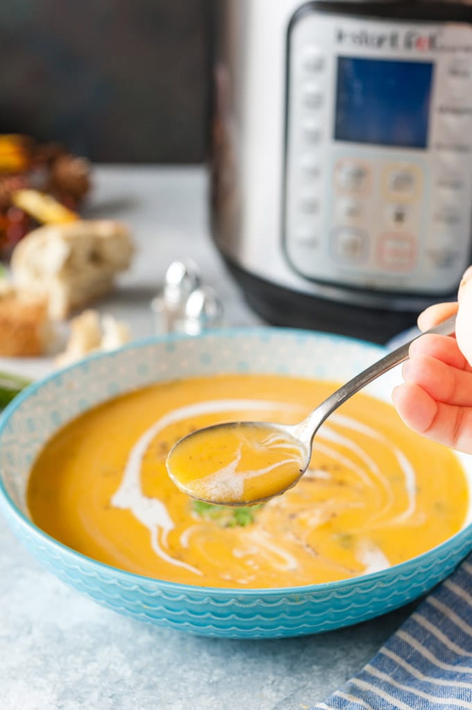Hand holding a spoon with soup.
