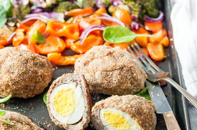 Cut up Baked scotch egg on a sheet pan with vegetables.
