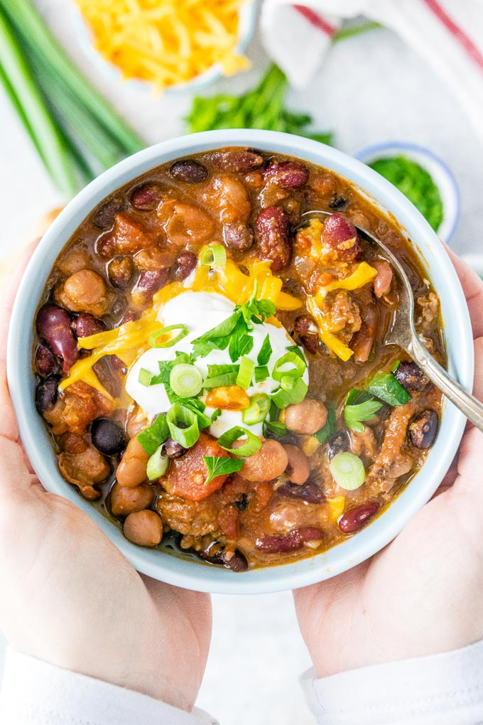 Hands holding a bowl of chili.