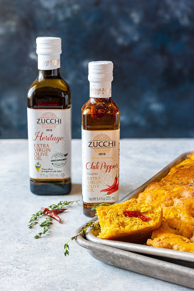 Pumpkin Focaccia on a tray with two bottles of Zucchi Extra Virgin Olive Oils behind it.